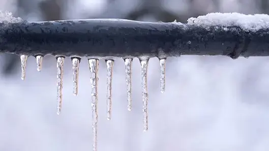 pipe frozen with snow on top and icicles hanging off of it